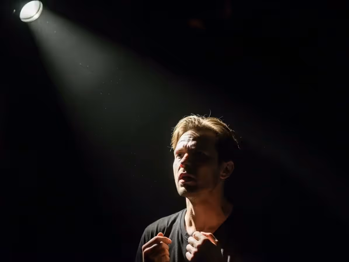 Escenario negro de teatro con un solo haz de seguidor sobre el actor
