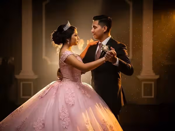 Quinceañera con tiara y vestido rosa bajo el seguidor durante su vals