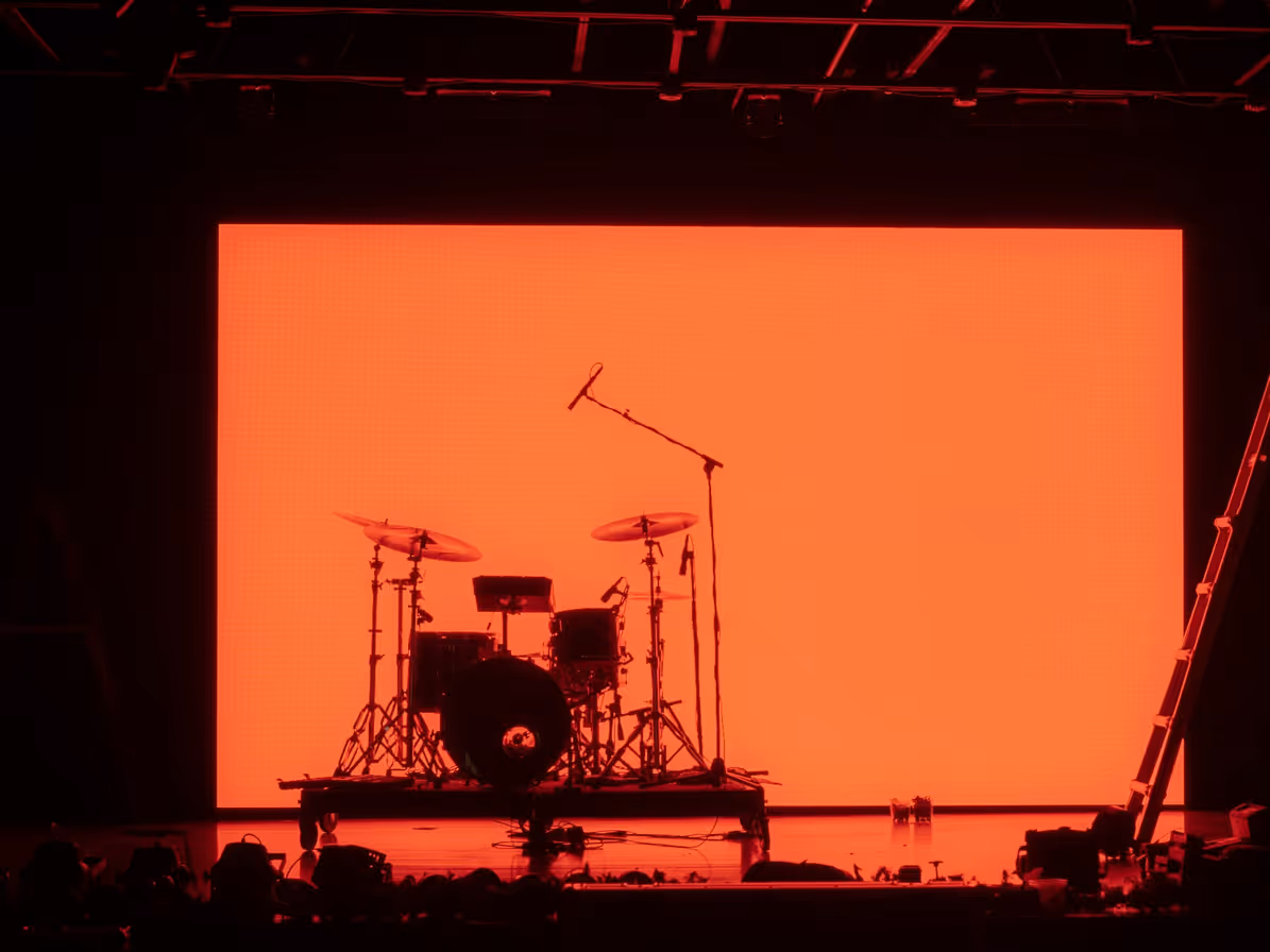 Batería sobre escenario frente a fondo naranja iluminado