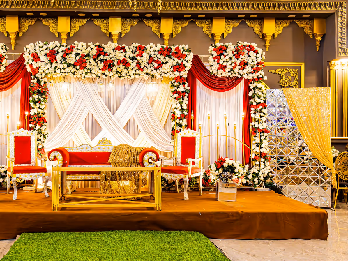 Escenario decorado con flores, cortinas y asientos en un salón