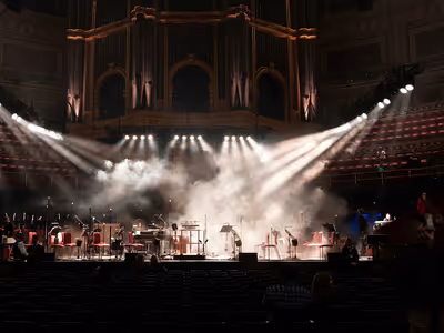 Orquesta sobre escenario bajo iluminación dramática en teatro