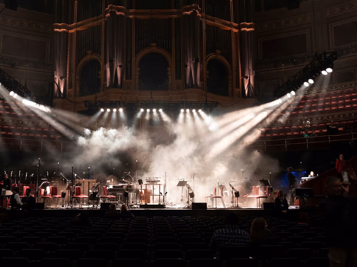 Orquesta sobre escenario bajo iluminación dramática en teatro
