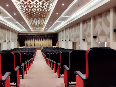 Auditorio vacío con butacas rojas frente a escenario