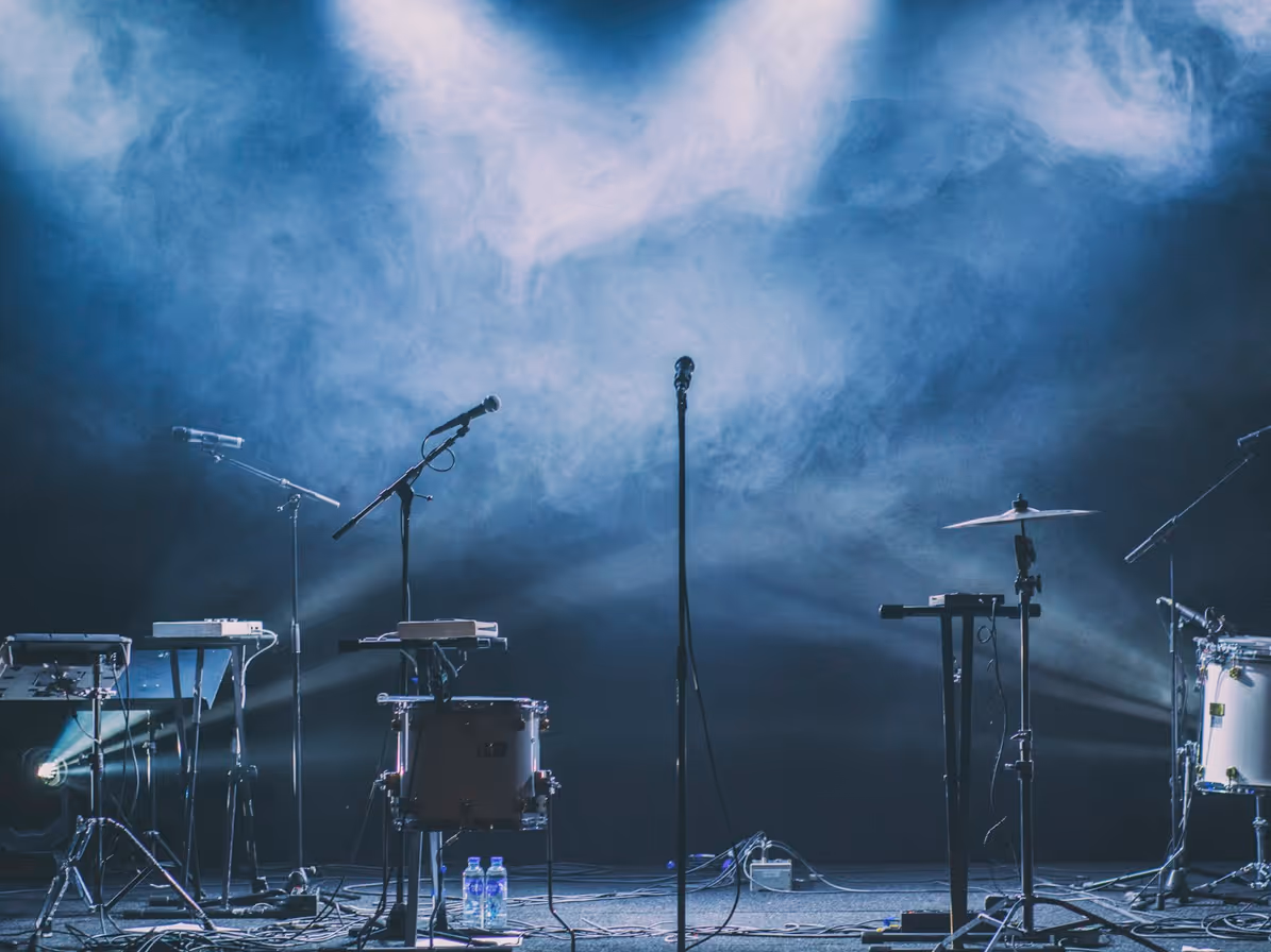Instrumentos sobre escenario con luces azules y neblina